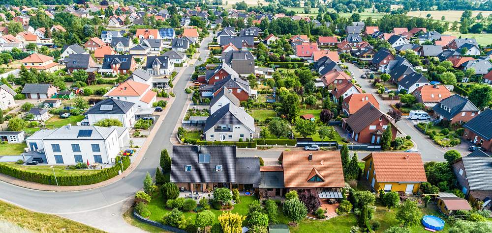 Typical German new housing development in the flat countryside of northern Germany between a forest and fields and meadows, made with drone